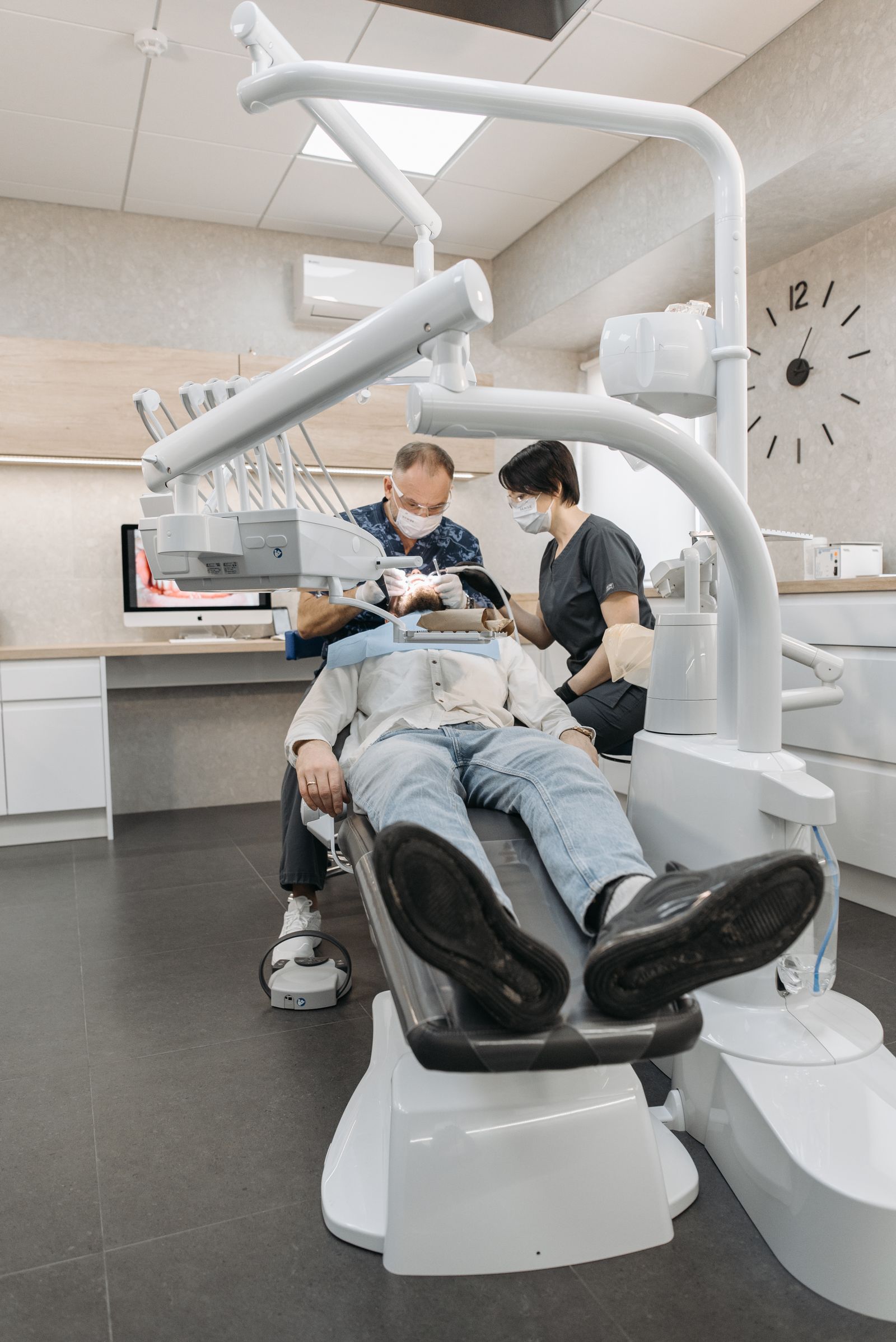 A dentist and assistant caring for a patient in a modern operatory
